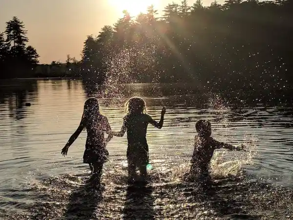 Silhouettes of children splashing and playing in Swains Lake during a golden sunset