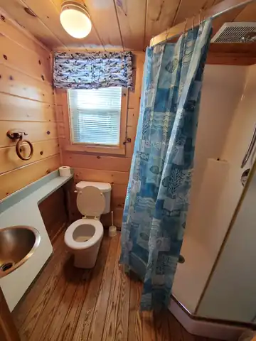 Private full bathroom inside the Deluxe Cabin featuring a shower, flush toilet, and sink