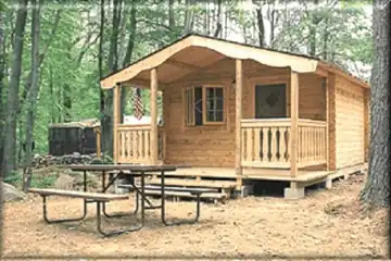 Exterior view of a Rustic Cabin rental featuring a covered porch and outdoor picnic table